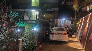 A two-story building with a car parked in front. - Hotel Om Palace (Mahabaleshwar)