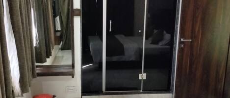 Une chambre d’hôtel avec un lit, une poubelle rouge, un placard à portes coulissantes et un appareil de climatisation.