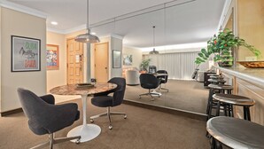 Ein Konferenzraum mit rundem Tisch, schwarzen Stühlen und einer Bar mit Hockern.