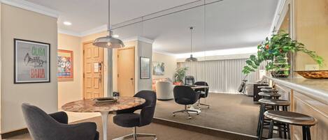 A conference room with a round table, black chairs, and a bar area with stools.