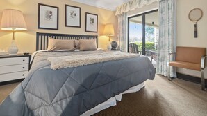 Ein Schlafzimmer mit einem großen Bett, zwei Nachttischlampen, einem Sessel und einem an der Wand hängenden Tennisracket.