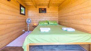A wooden cabin room with a bed, a fan, and a sign on the wall. - Picturesque Escape Holiday Home With Pool and Sauna (Kastela)