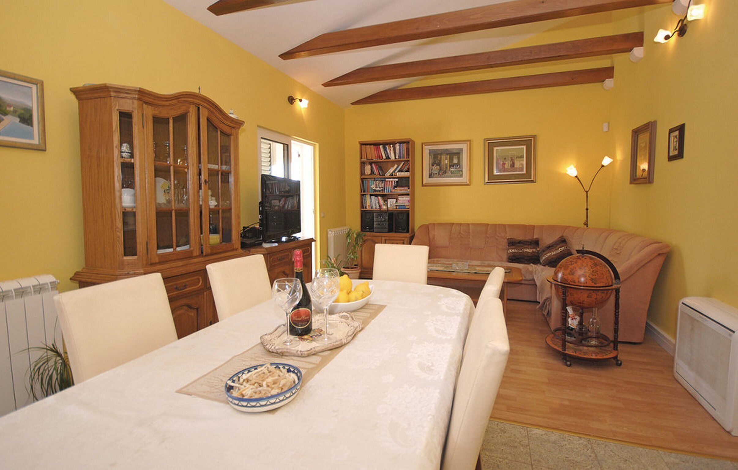 Un comedor con una mesa dispuesta para dos, un sofá y una estantería.