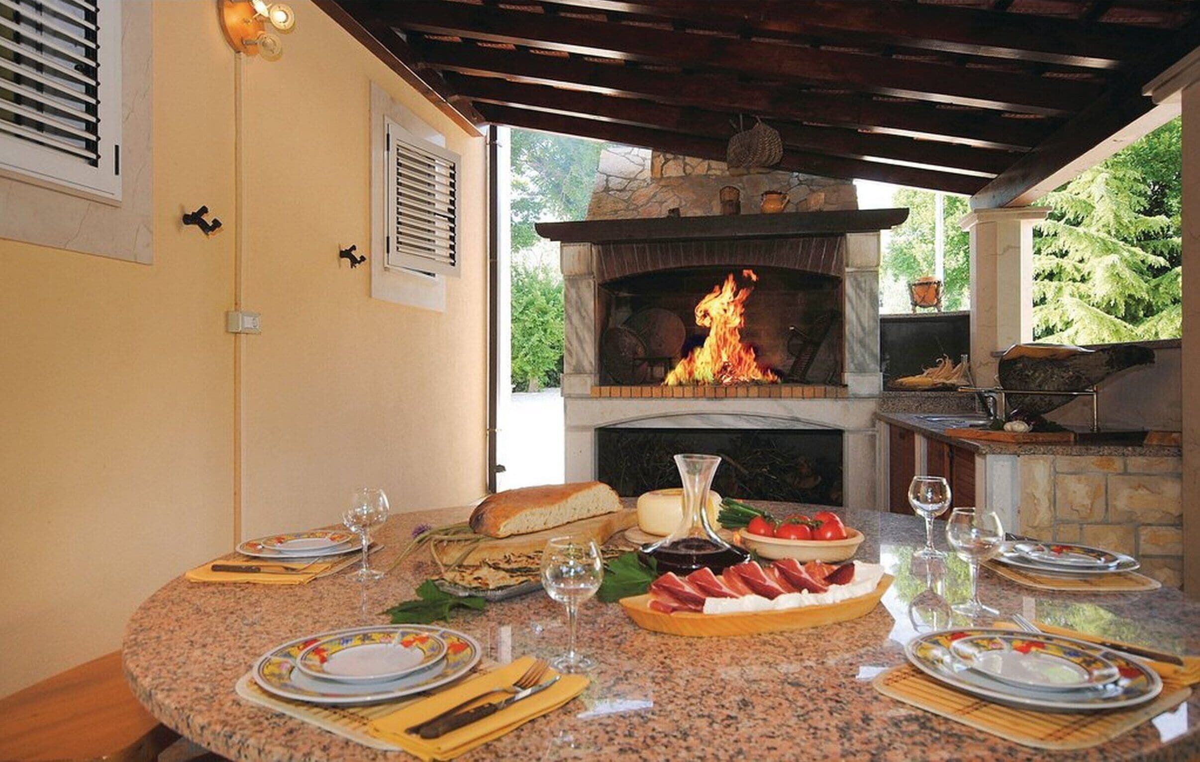 Cocina exterior con chimenea de piedra y mesa lista para una comida.
