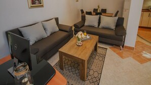 A modern living room with a sofa, a coffee table, and a dining area.