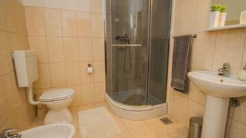 Ein Badezimmer mit Toilette, Bidet, Waschbecken und einer Duschkabine.