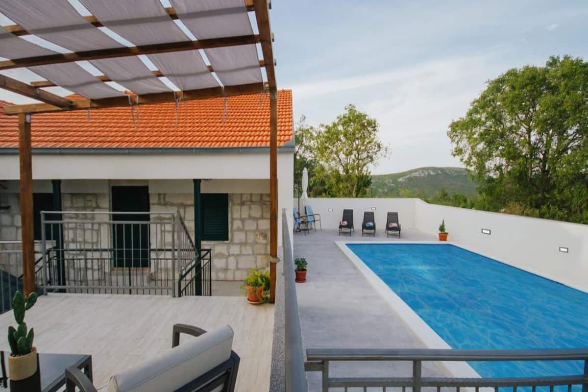 Un espace aménagé au bord de la piscine, comprenant une piscine, des chaises longues et une pergola.