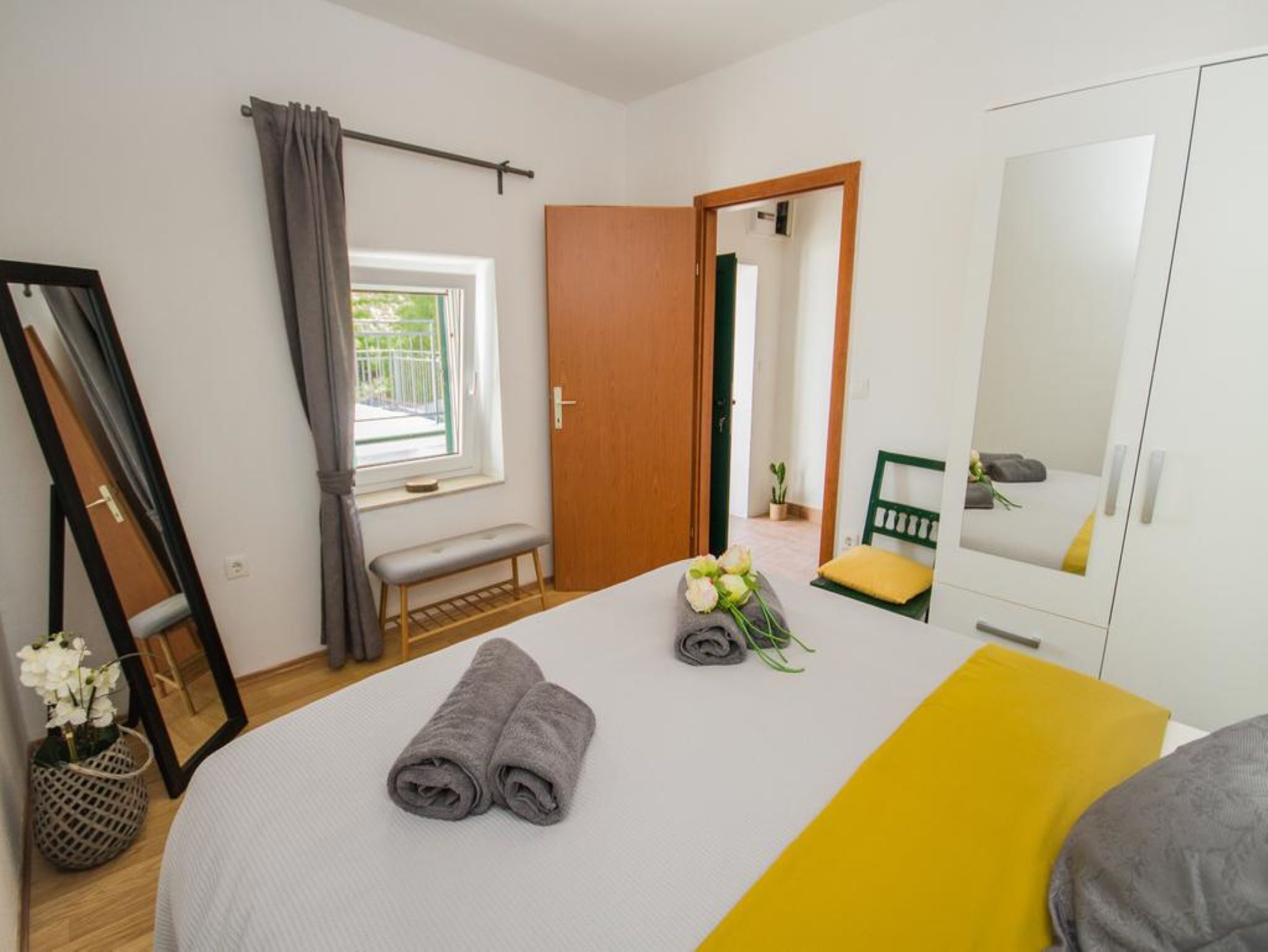 Ein Schlafzimmer mit Bett, Sitzbank, Spiegel und Kleiderschrank.