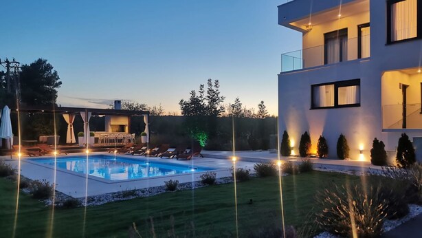 Een modern herenhuis met zwembad, buitenmeubilair en goed verlichte paden.