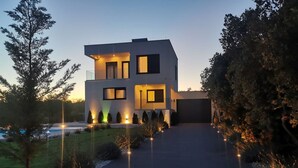 Een modern huis met twee verdiepingen en een oprit die naar de garage leidt.