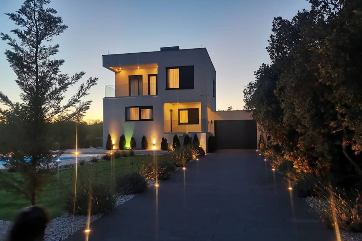 Une maison moderne à deux étages avec une allée menant au garage.