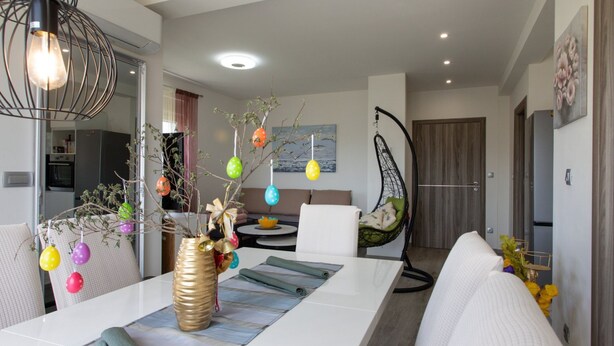 Un salón moderno con una mesa de comedor, una silla colgante y una cocina al fondo.