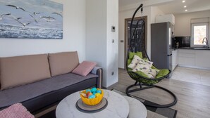 Una sala moderna con un sofá, una silla colgante y una mesita con una cesta.