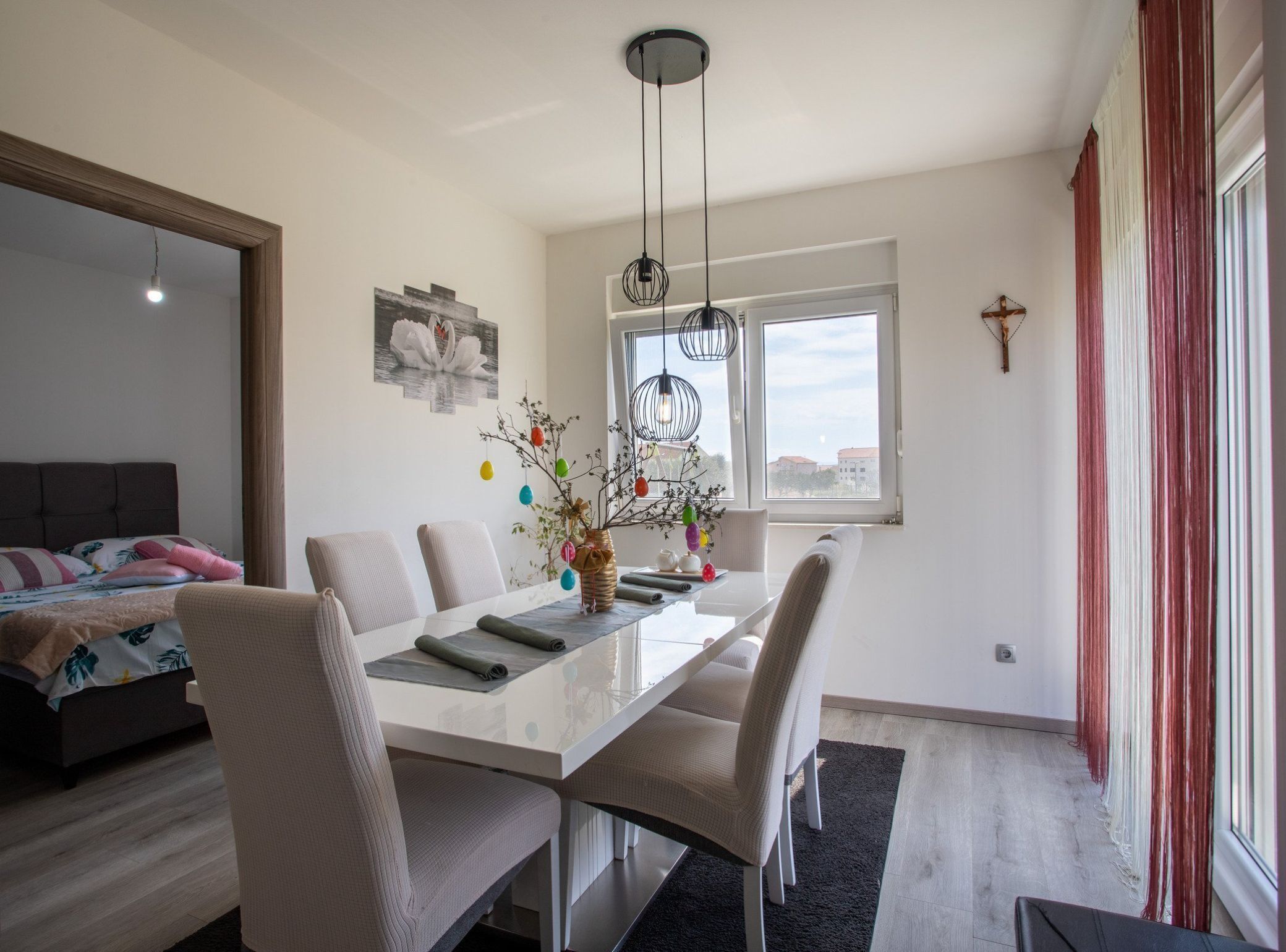 Een moderne eetruimte met een witte tafel, beige stoelen en een vaas met kleurrijke decoraties.