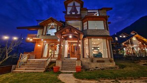 A multi-story house with a prominent staircase, large windows, and a well-lit entrance. - Hygge Home Manali (Manali)