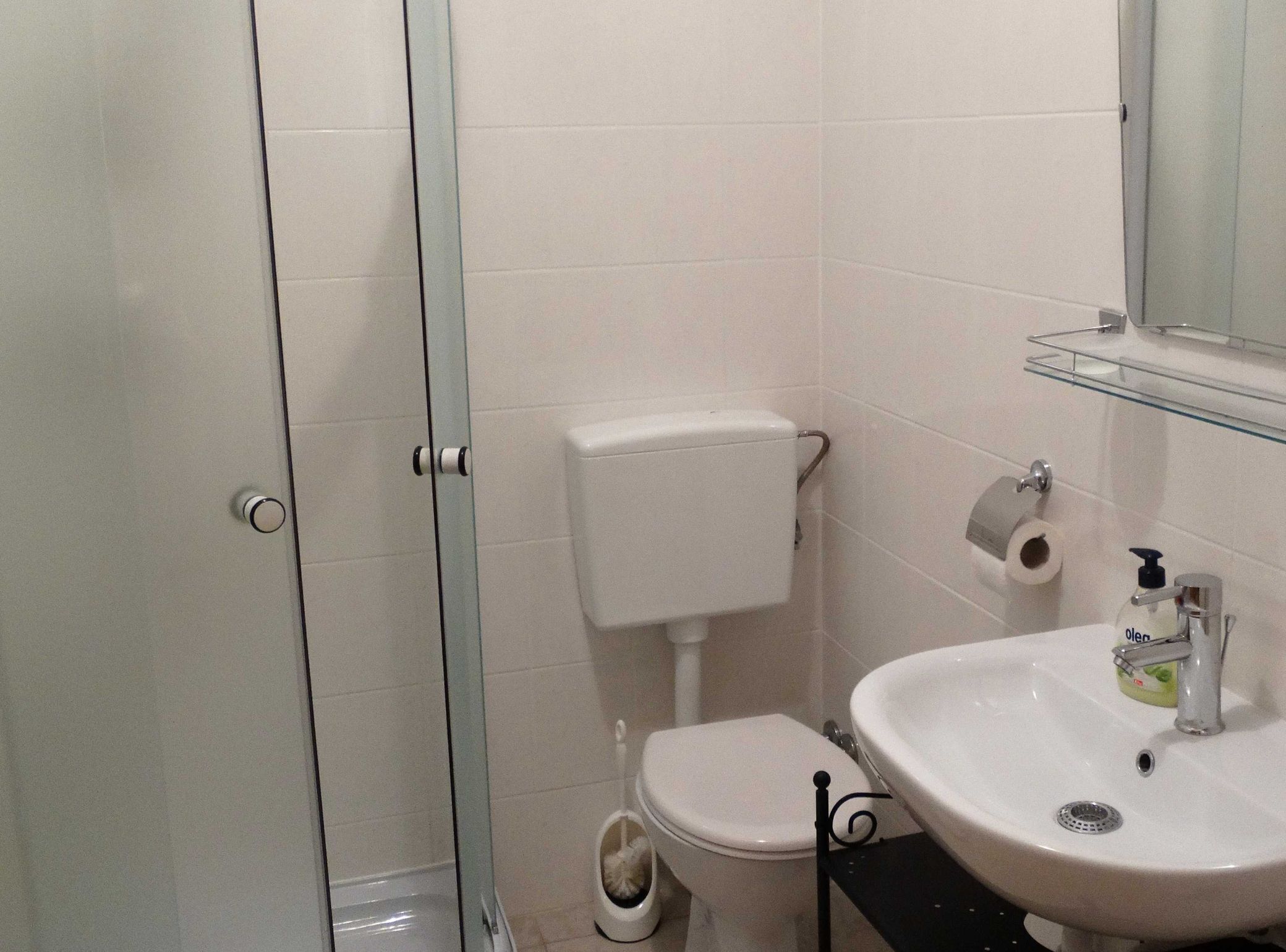 A bathroom with a toilet, a sink, and a glass shower enclosure.