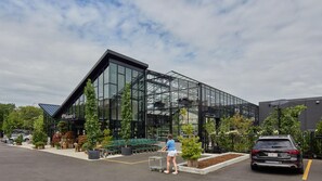 Un bâtiment moderne doté de grandes fenêtres en verre, d’un parking et d’une personne qui pousse un chariot de courses.