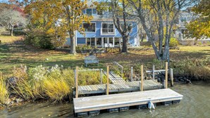 A house with a dock extending into a river. - Waterfront Retreat with Private Dock and Fire Pit  |  Sleeps 8, Outdoor Dining, Spa-Style Primary, Chef’s Kitchen w/ Dual Dishwashers, Gas Fireplace, River Views, Bright Open Layout, Central A/C, Perfect Coastal Escape for Families, 24 Hr Hospitality (Falmouth)