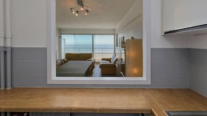 A modern kitchen with a wooden countertop, a built-in oven, and a view of a balcony with a dining area.