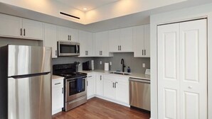 Una cocina moderna con armarios blancos, electrodomésticos de acero inoxidable y suelo de madera.