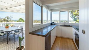 Eine moderne Küche mit großen Fenstern, einer Holzterrasse und Blick auf die Landschaft.