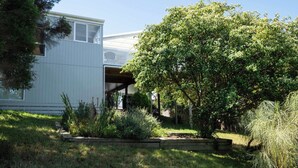 Ein modernes Haus mit einer überdachten Veranda, umgeben von üppiger Vegetation und einem gepflegten Garten.