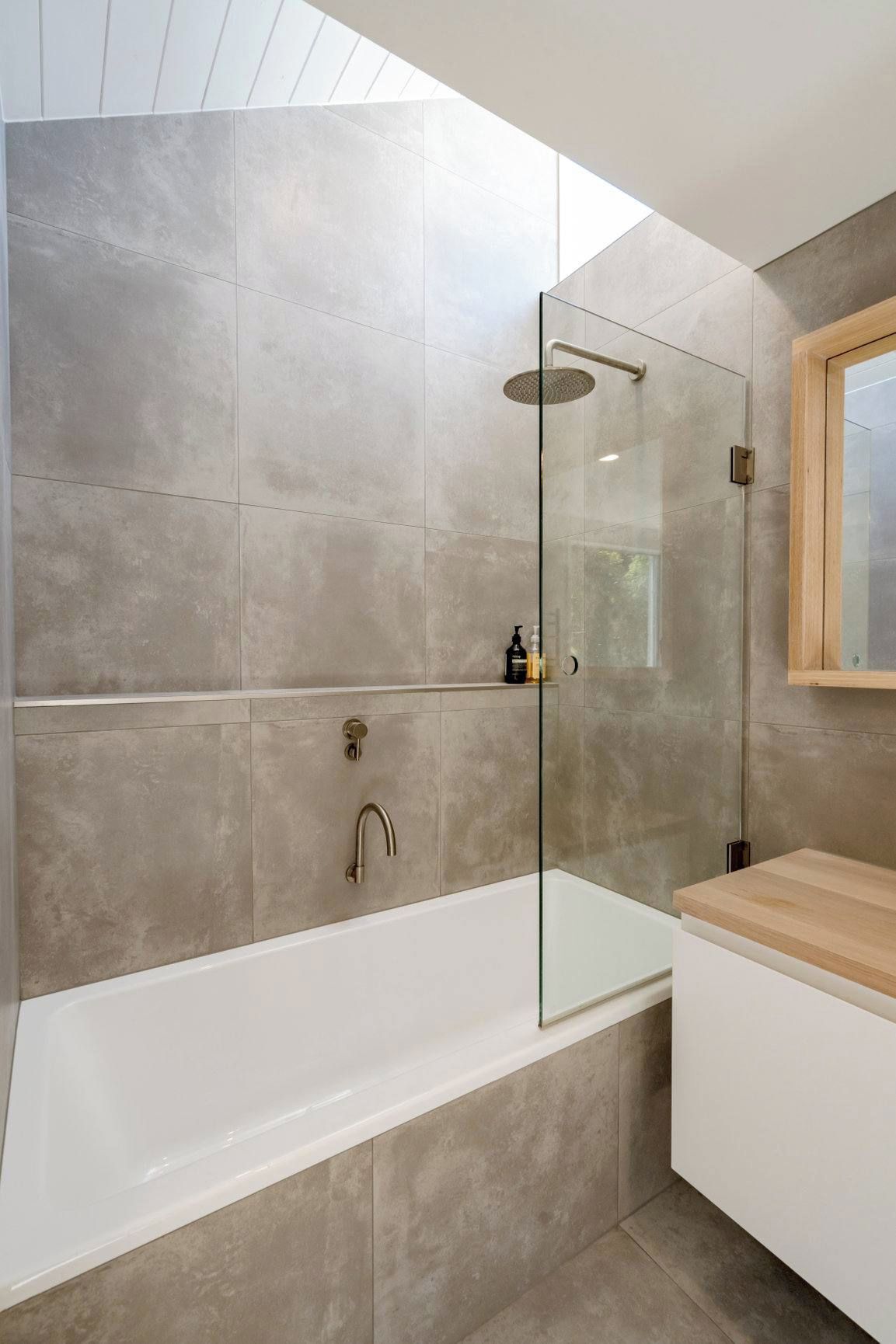 A modern bathroom with a glass-enclosed shower, a freestanding bathtub, and a wooden vanity.