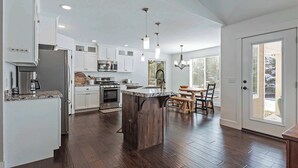 A modern kitchen with white cabinets, a central island, and a dining area with a table and chairs. - 10 Minutes to the Unitas! Full-Home Francis Rental (Kamas)