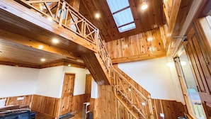 A wooden interior with a staircase connecting two floors, a door, and a window. - Singing Woods Kutla (Bhuntar)