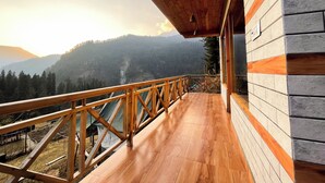 A wooden deck with a railing overlooking a mountainous landscape. - Singing Woods Kutla (Bhuntar)