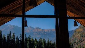 A room with a large window overlooking a mountainous landscape. - Singing Woods Kutla (Bhuntar)