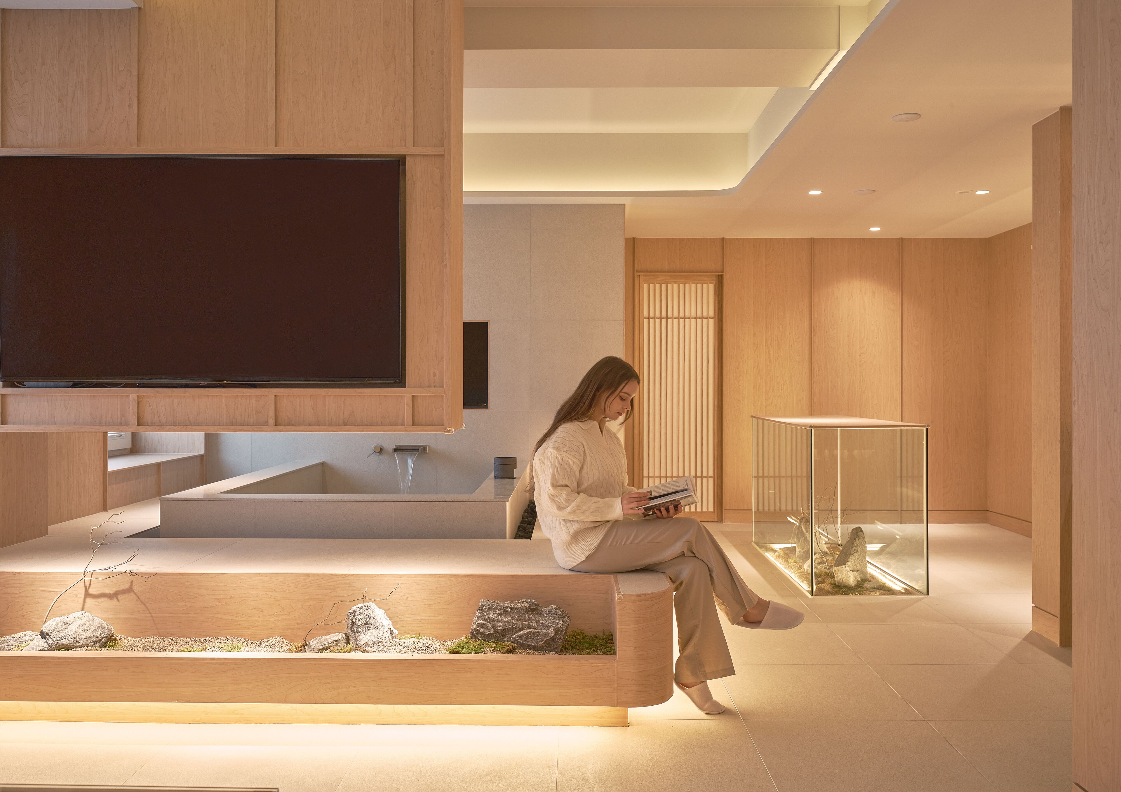 A modern interior with a large flat-screen TV, a built-in bathtub, and a seating area with a glass display case.