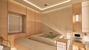 A modern bathroom with a freestanding bathtub, wooden paneling, and a built-in vanity with a mirror. - UH Continental CenterPoint (Busan)