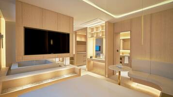 Una habitación de hotel moderna con una cama grande, televisión, bañera, una mesita y un espejo.