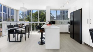 Una cocina moderna con una isla grande, muebles blancos y un refrigerador negro.