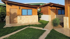 Un edificio moderno de madera con techo verde, pared de piedra y césped cuidado.
