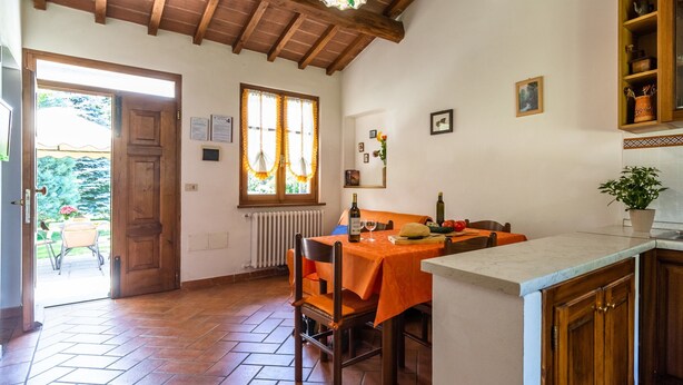 Un comedor con una mesa dispuesta para dos, techo de madera y vistas a través de una ventana.