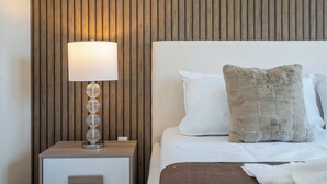 A neatly made bed with a white and brown pillow, a bedside lamp, and a wooden panel wall. - Luxury 3BR home with Mario Bros Room Near Disney (Kissimmee)