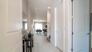 A hallway with a dining area, a staircase, and a door. - Luxury 3BR home with Mario Bros Room Near Disney (Kissimmee)