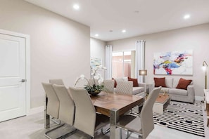 Un espace repas moderne avec une table en bois, des chaises de couleur beige et une orchidée décorative en guise de centre de table.