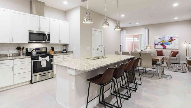 A modern kitchen with white cabinets, stainless steel appliances, and a central island with bar stools.