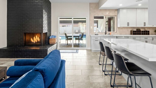 Una cocina moderna con una isla central, una chimenea y un comedor con vistas.