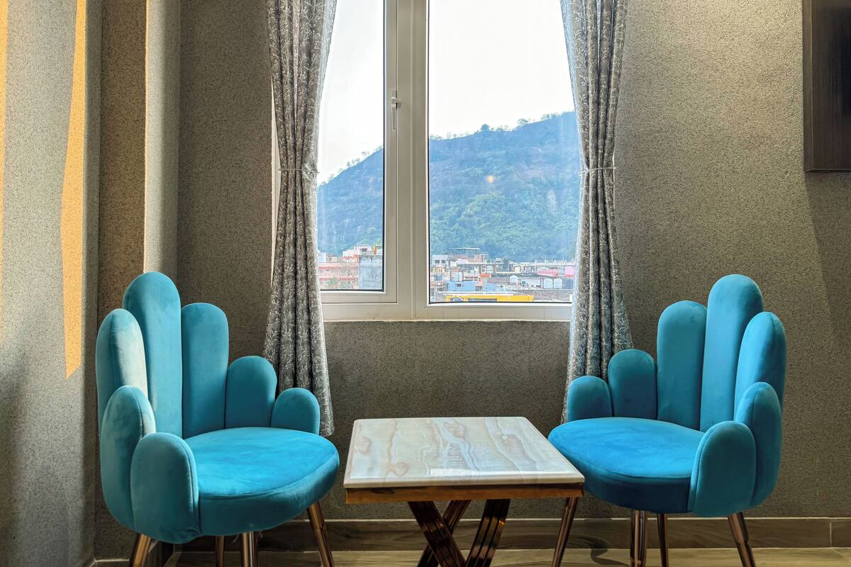 A room with two blue armchairs, a wooden table, and a window with curtains.