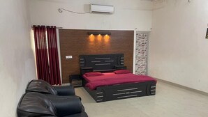 Un dormitorio con cama, sofá, aire acondicionado instalado en la pared y un tablón de anuncios.