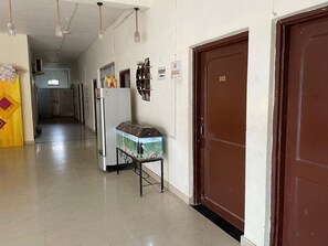 A hallway with a fish tank, a refrigerator, and a door with the number 102. - Lord Buddha Guest House (Gorakhpur)