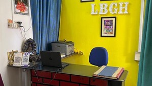 Un mostrador de recepción con una pared amarillo brillante, cuadros enmarcados y un letrero que dice "LBGH".