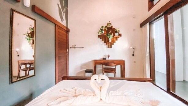 A hotel room with a bed, a desk, a chair, a mirror, and a wall-mounted plant. - The Moon House for Entrepreneurs (Dalung)