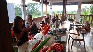 A group of people seated around a wooden table with laptops, surrounded by potted plants and a laptop on the table. - The Moon House for Entrepreneurs (Dalung)