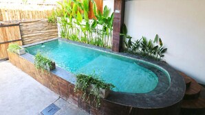 A swimming pool with a curved edge, surrounded by a wooden deck and various plants. - The Moon House for Entrepreneurs (Dalung)