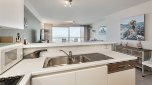 A modern kitchen with a built-in dishwasher, stainless steel sink, and a large window offering a view of the city. - Apartment in Blankenberge by the Beach (Blankenberge)